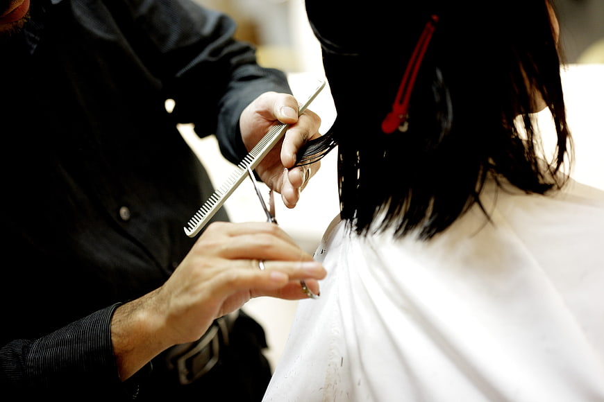Close-up of hairdresser cutting woman's hair with scissors