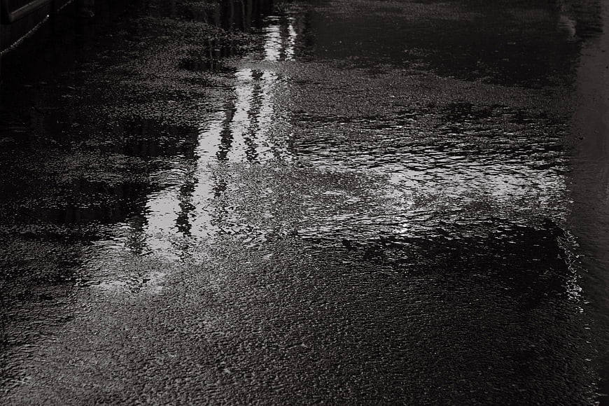 Black and white abstract wet asphalt texture with light reflection