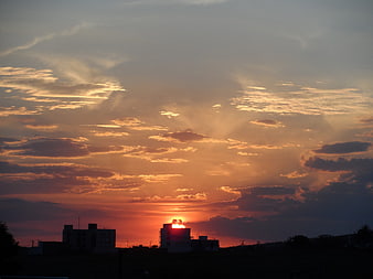 Dramatic sunset with sun rays over silhouetted buildings