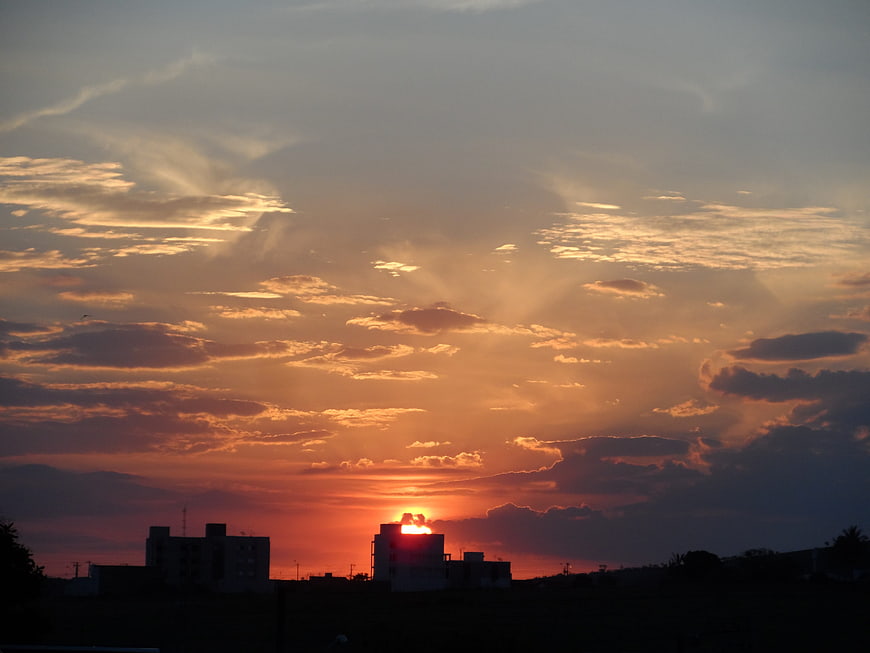 Dramatic sunset with sun rays over silhouetted buildings