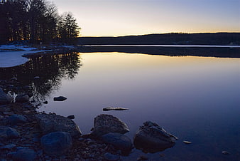 Serene Lake at Sunset with Rocky Shoreline and Reflections