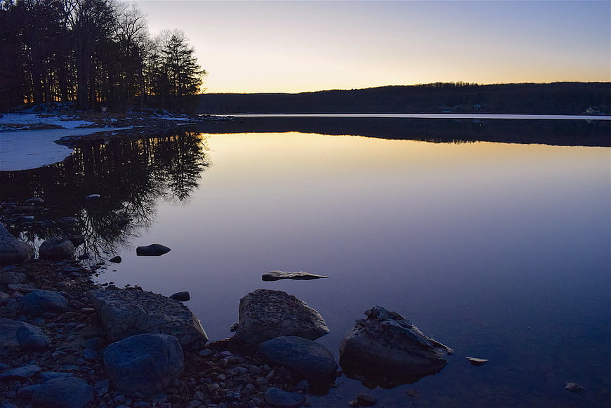 Serene Lake at Sunset with Rocky Shoreline and Reflections