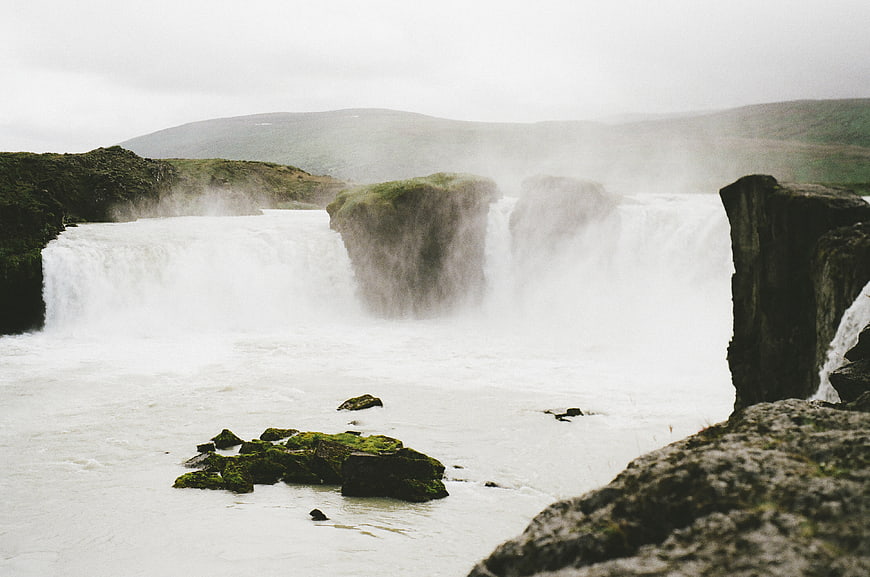 Misty waterfall cascading over mossy rocks in a rugged landscape