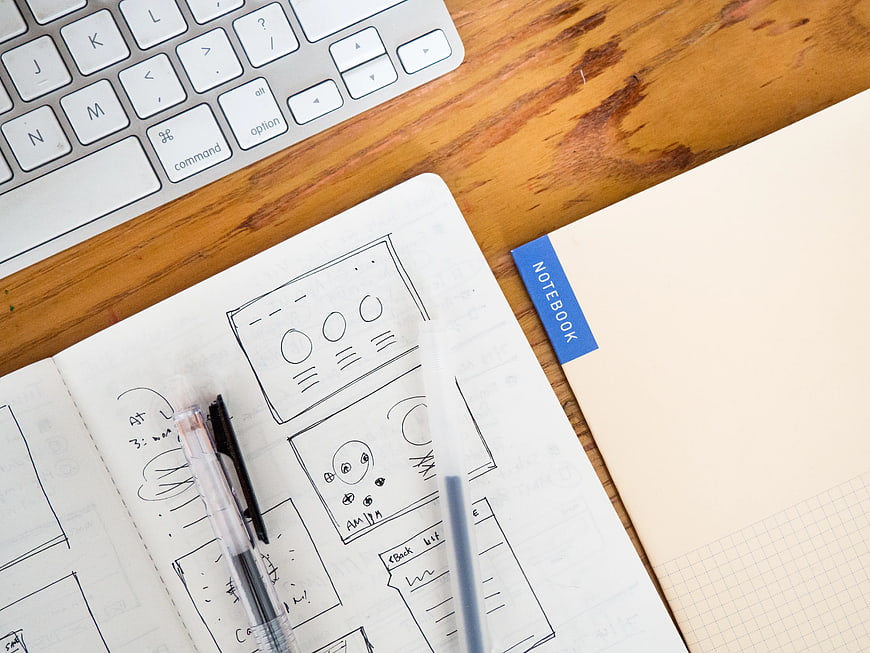 UX Design Sketches on Wooden Desk with Keyboard