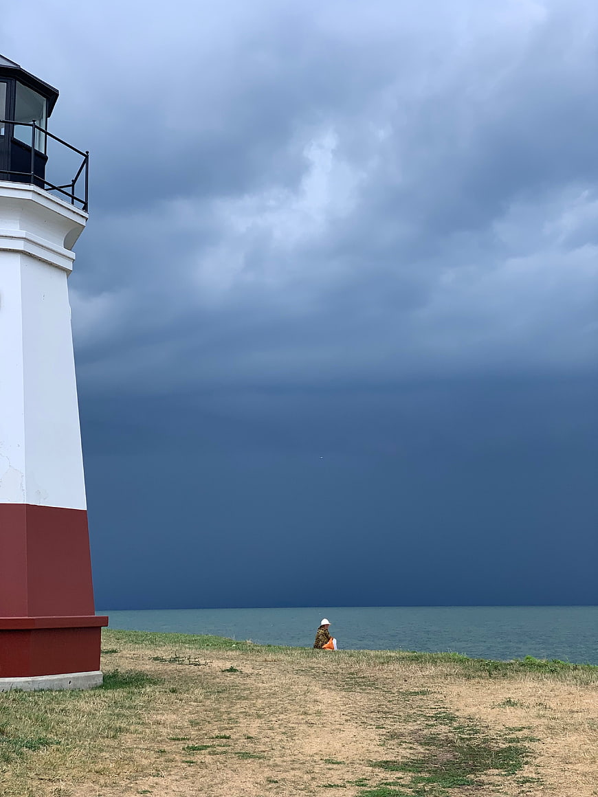 Lighthouse on Lake Shore Under Stormy Sky