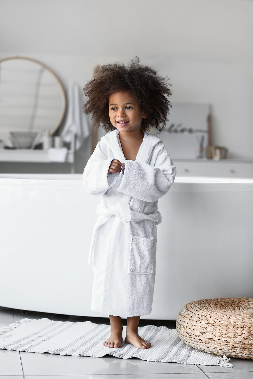 Cute little girl with curly hair in white bathrobe