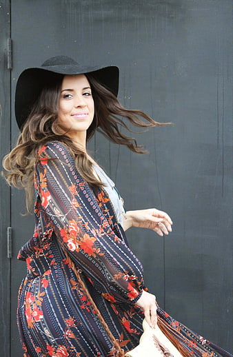Stylish woman in floral dress and black hat outdoors