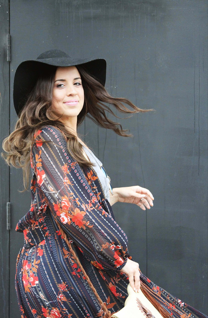Stylish woman in floral dress and black hat outdoors