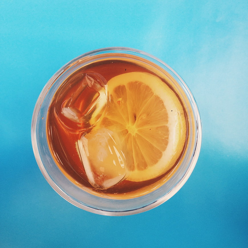 Top view of iced tea with lemon slice on blue background