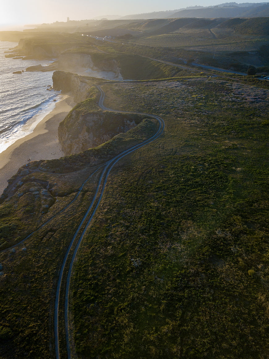 Aerial view of winding coastal road along cliffs at sunset