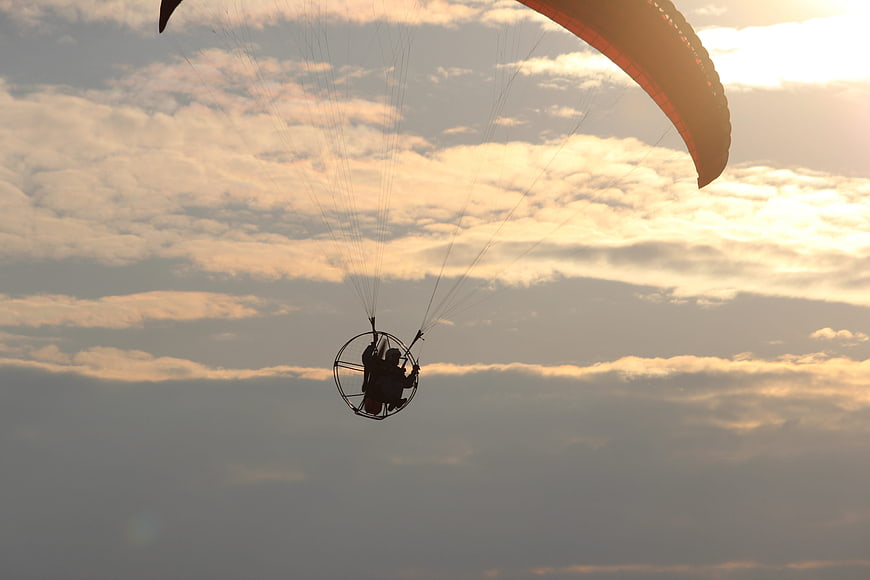 Silhouette of Paraglider Flying Against Golden Sunset Sky