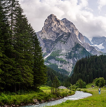 Hiker in Alpine Valley with Majestic Mountain Peak and Stream