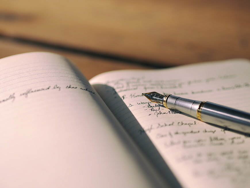 Close-up of fountain pen on handwritten notebook