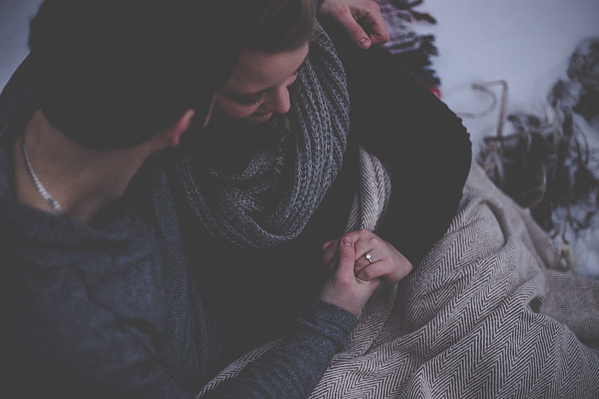 Couple Holding Hands With Ring Under Blanket
