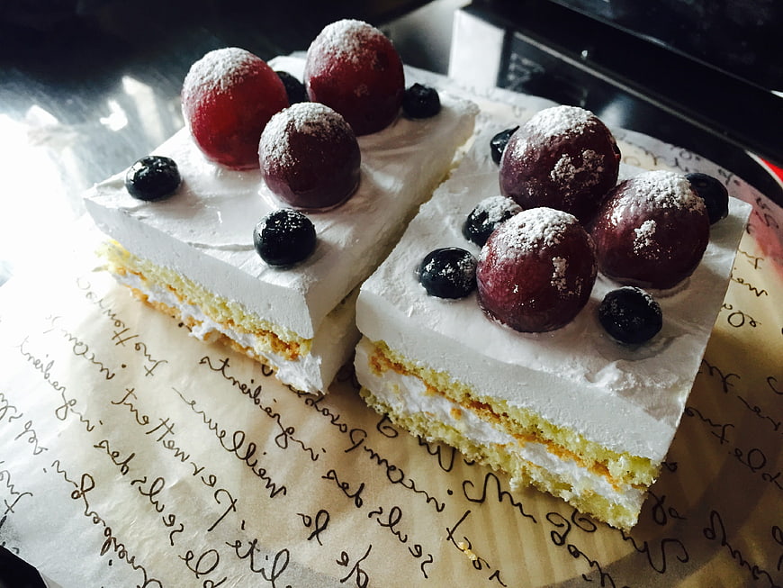 Homemade layered cake with plums and blueberries on parchment paper