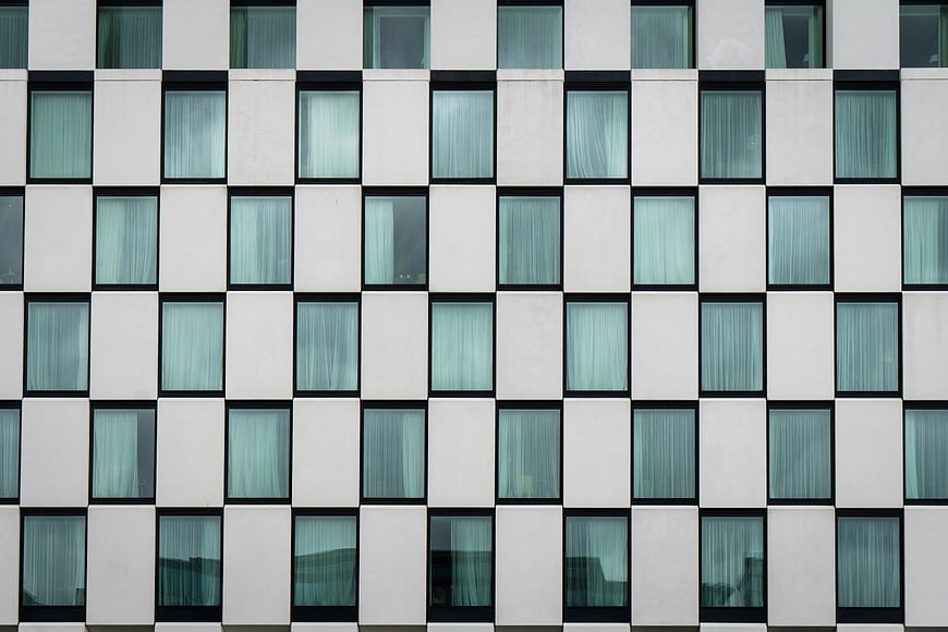 Modern white building facade with grid of blue windows