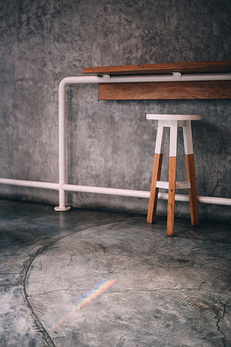 Minimalist industrial interior with wooden stool and rainbow light