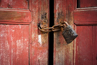 Rusty Padlock Securing Weathered Red Wooden Barn Door