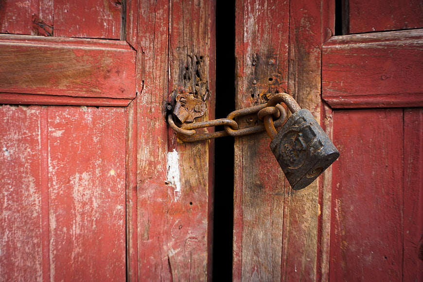 Rusty Padlock Securing Weathered Red Wooden Barn Door