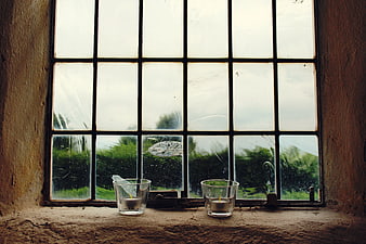 Two Tea Lights on Rustic Windowsill with Rainy View