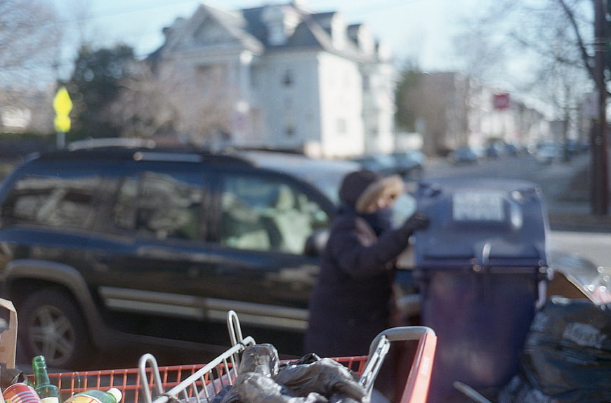 Blurred street scene of person with shopping cart and trash