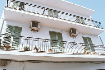 White apartment building with green shutters and balconies