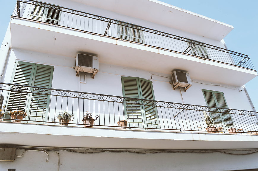 White apartment building with green shutters and balconies