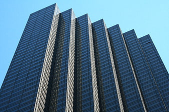 Low angle view of modern glass skyscraper against blue sky