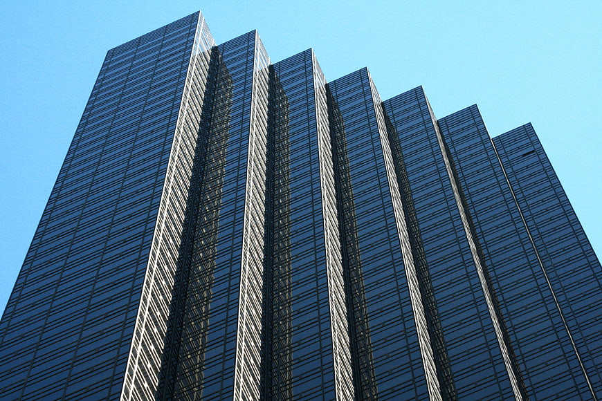 Low angle view of modern glass skyscraper against blue sky
