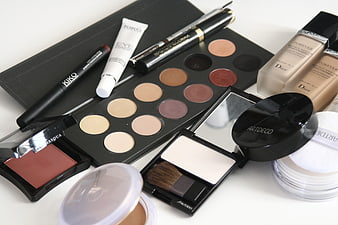 Flat lay of luxury and drugstore makeup products on white background