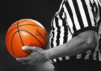 Basketball referee holding orange ball in black and white