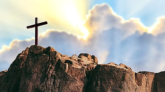 Wooden cross on rocky mountain peak with divine light rays in cloudy sky