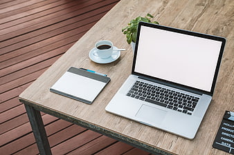High angle view of laptop workspace with coffee and notebook