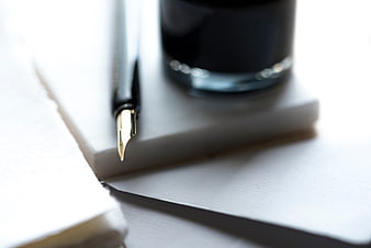 Close-up of fountain pen and ink bottle on notebook