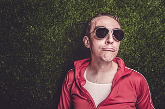 Young man in red jacket and sunglasses making a funny face