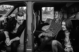 Three men sitting inside a van in black and white