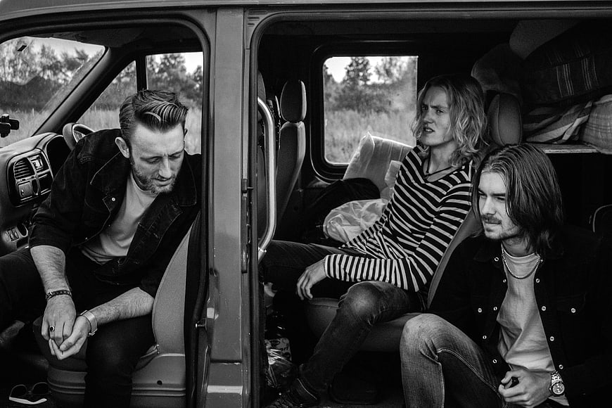 Three men sitting inside a van in black and white
