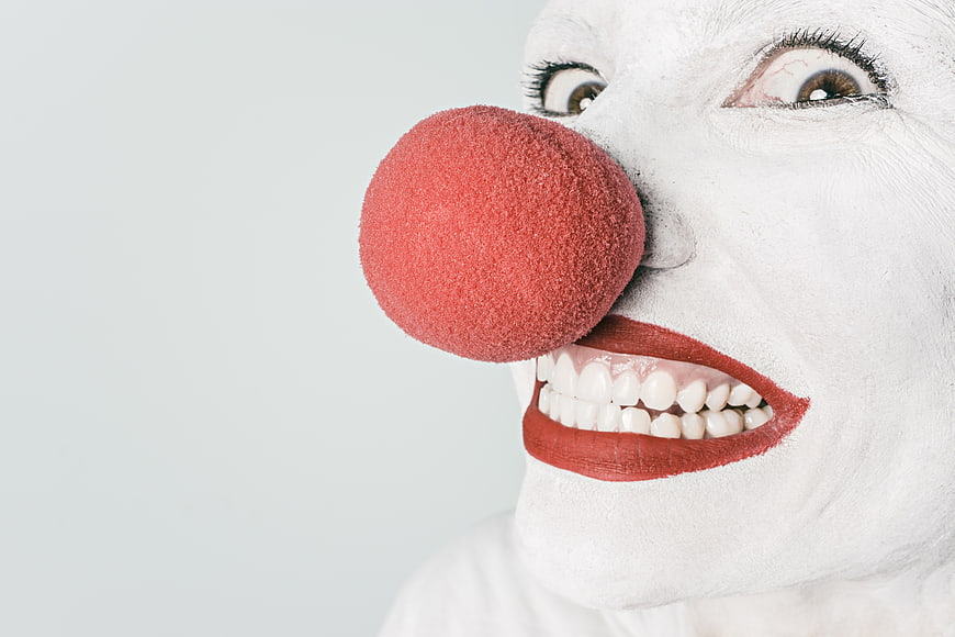 Close-up of creepy clown face with red nose and white makeup