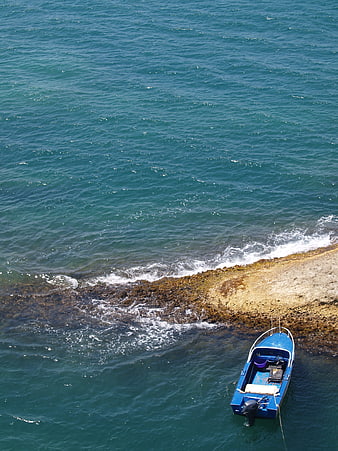 Aerial view of blue motorboat near rocky coastline