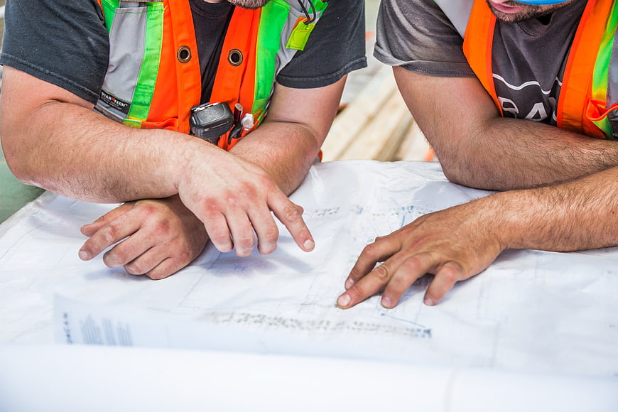 Construction workers reviewing blueprints on site