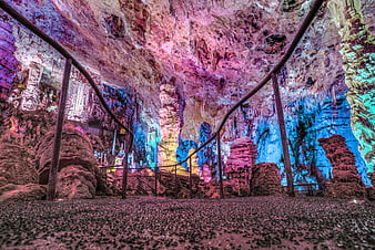 Colorful illuminated cave interior with stalactites and walkway