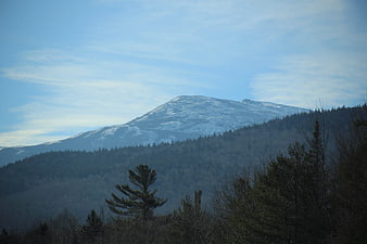 Snow-capped mountain peak rising above forested hills