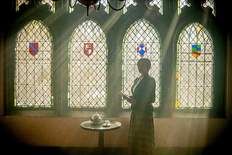 Woman reading book in front of stained glass windows