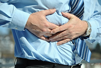 Businessman clutching stomach in pain outdoors