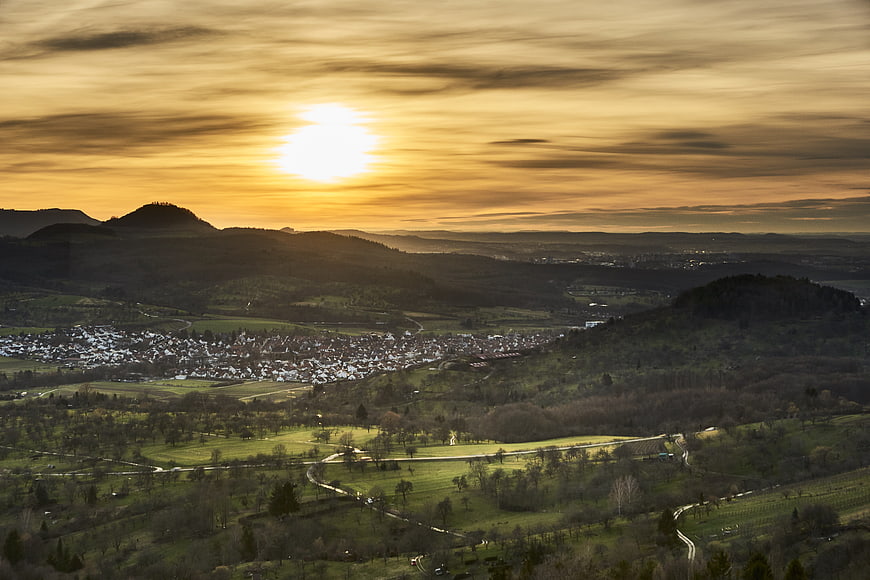 Panoramic sunset over rolling hills and village