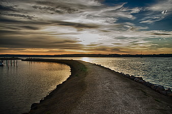 Dramatic sunset over a coastal breakwater and calm sea