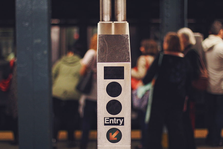 Subway turnstile entry sign with blurred commuters