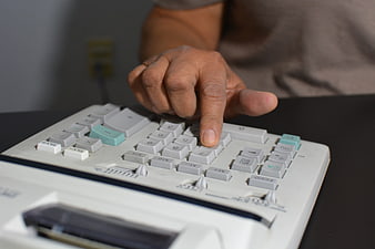 Close-up of hand pressing button on vintage desktop calculator