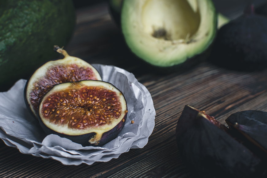 Fresh sliced figs and avocado on dark wood