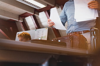 Businessman holding documents with briefcase in office